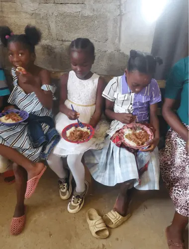feeding young kids in Raphaella Lewis Foundation